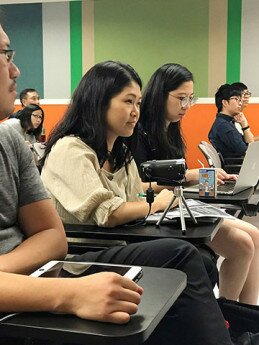 Brenda (middle) records the sign language interpretation by camera during the class so that she can study it later without missing a beat.