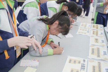 參與活動的小學生在攤位遊戲前寫下希望感謝的人與事
