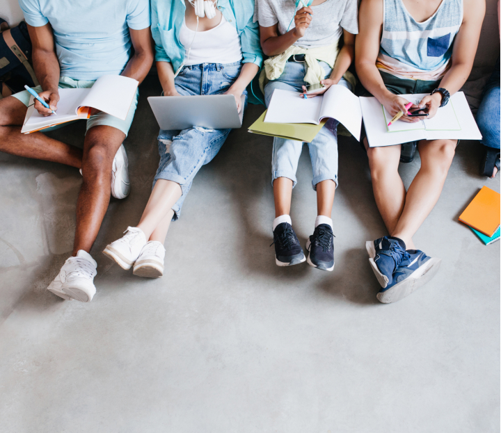 overhead-portrait-young-people-with-laptops-smartphones-sitting-together-floor-students-writing-lectures-holding-textbooks-their-knees